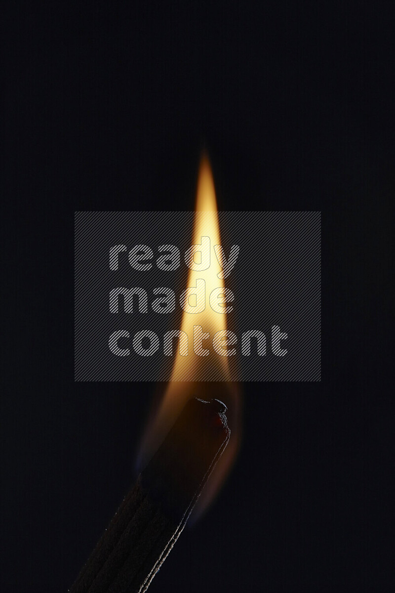 A burning incense stick isolated on dark backdrop