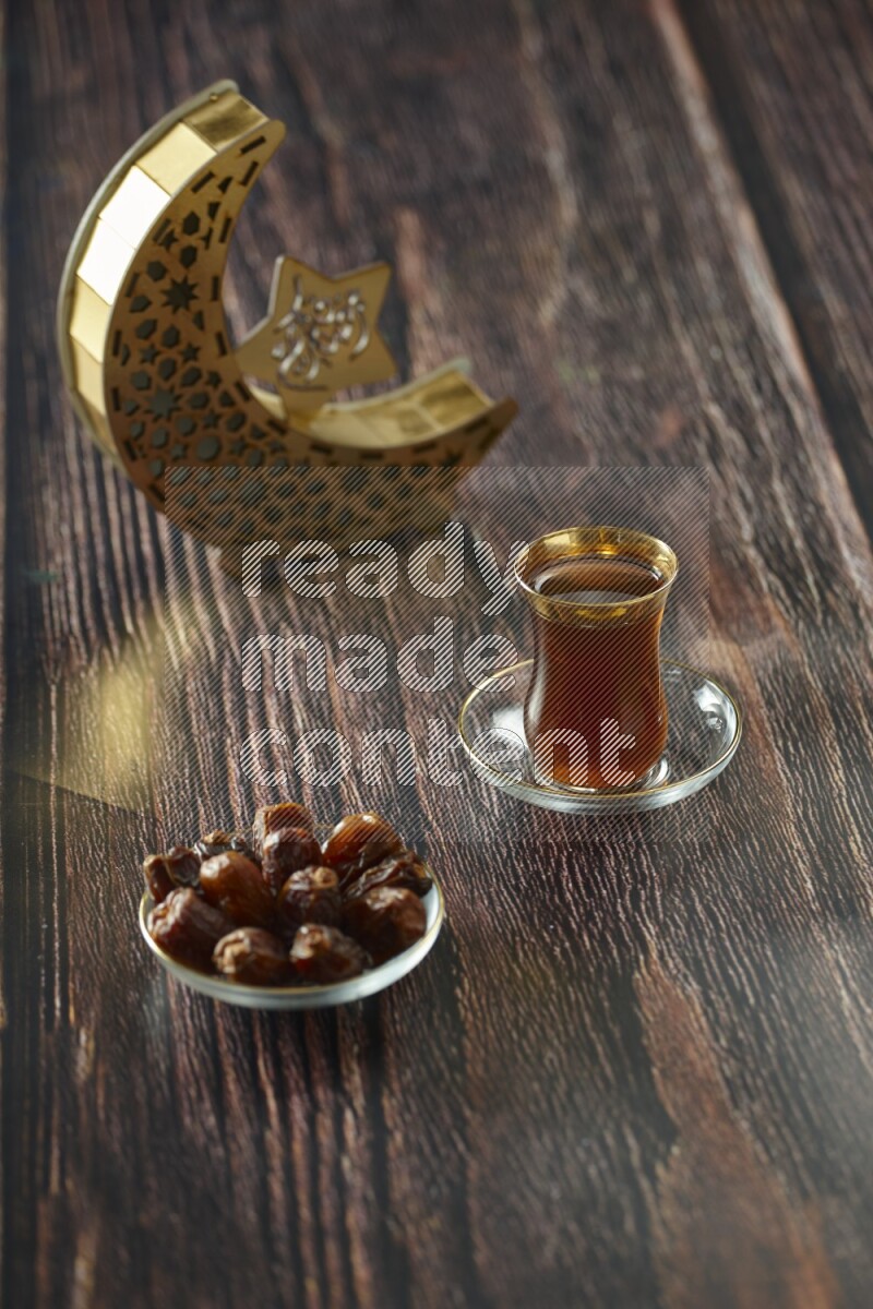 A wooden golden crescent lantern with different drinks, dates, nuts, prayer beads and quran on brown wooden background