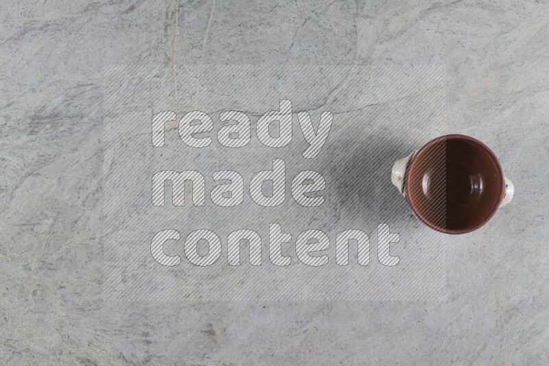 إناء فخاري متعدد الألوان مع غطائه على خلفية من الرخام الرمادي