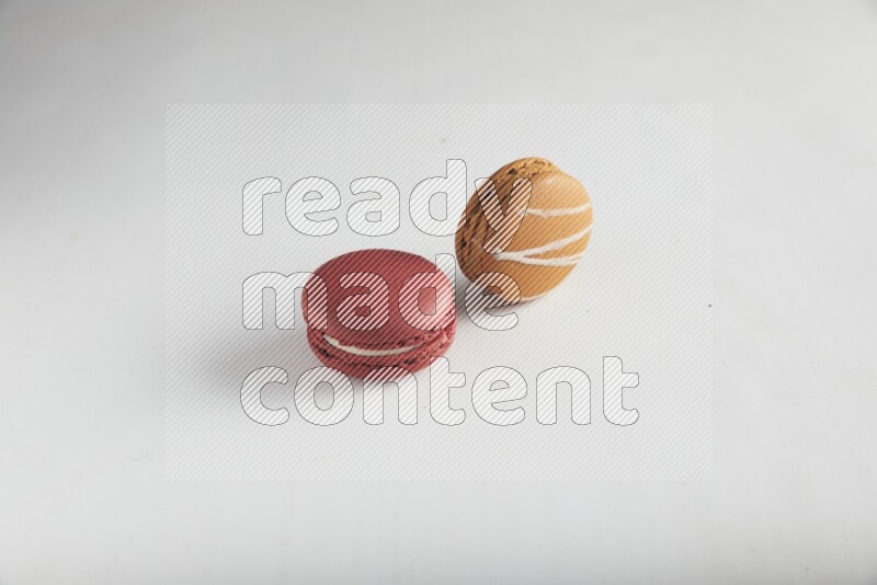45º Shot of of two assorted Brown Irish Cream, and Red Velvet macarons on white background