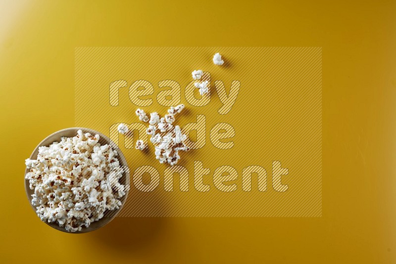 A multicolored ceramic plate full of popcorn with popcorn beside it on a yellow background in different angles