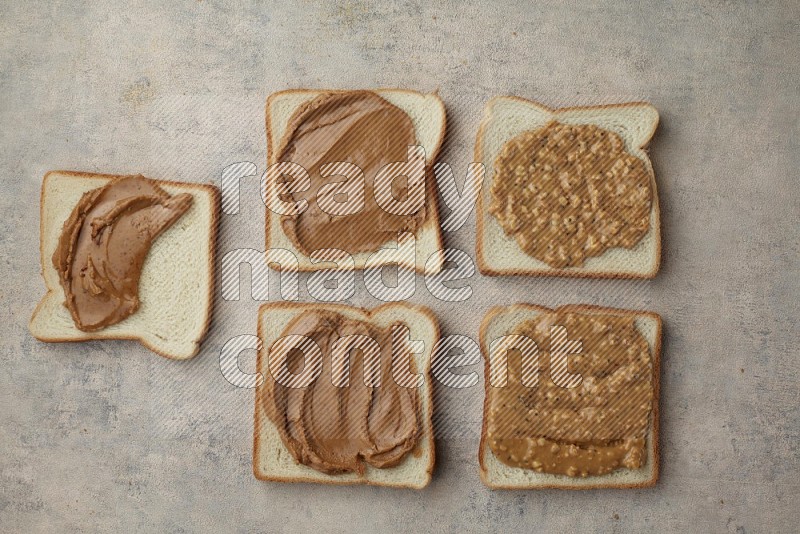 Creamy and Crunchy peanut butter on a white toast on a light blue textured background