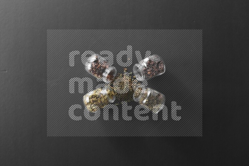 قرنفل وحبوب الهيل وريحان مجفف ويانسون نجمي في أوعية زجاجية علي خلفية سوداء