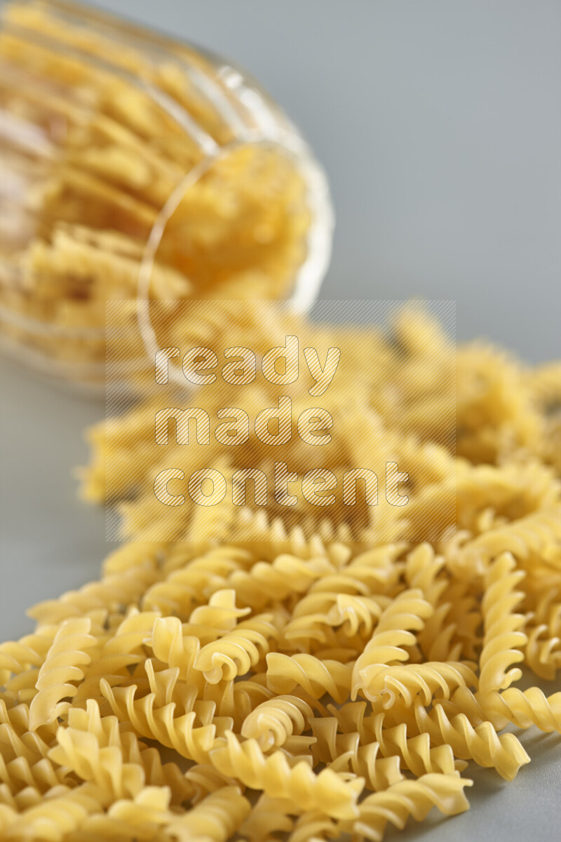 Flipped jar full of raw pasta on light blue background