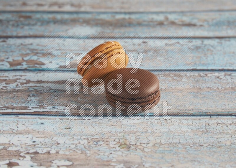 45º Shot of of two assorted Brown Irish Cream, and Brown Dark Chocolate macarons on light blue background