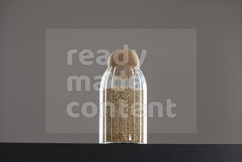 Hulled wheat in a glass jar on black background
