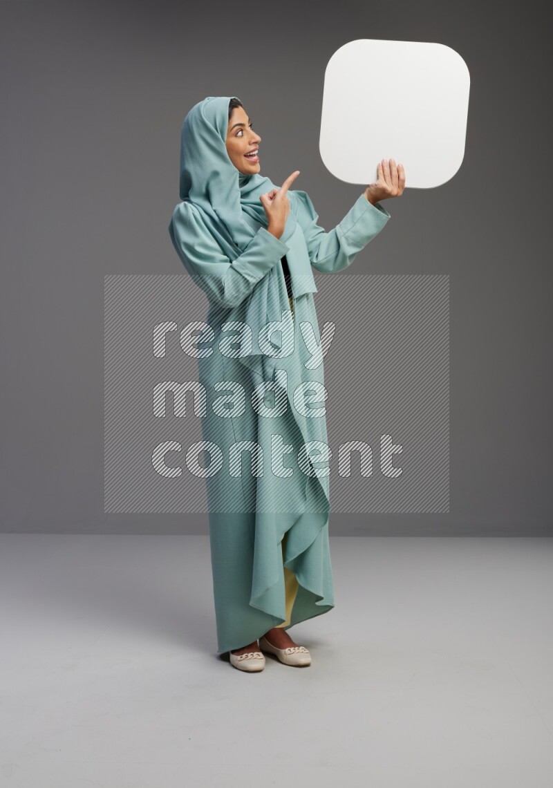 Saudi Woman wearing Abaya standing holding social media sign on Gray background