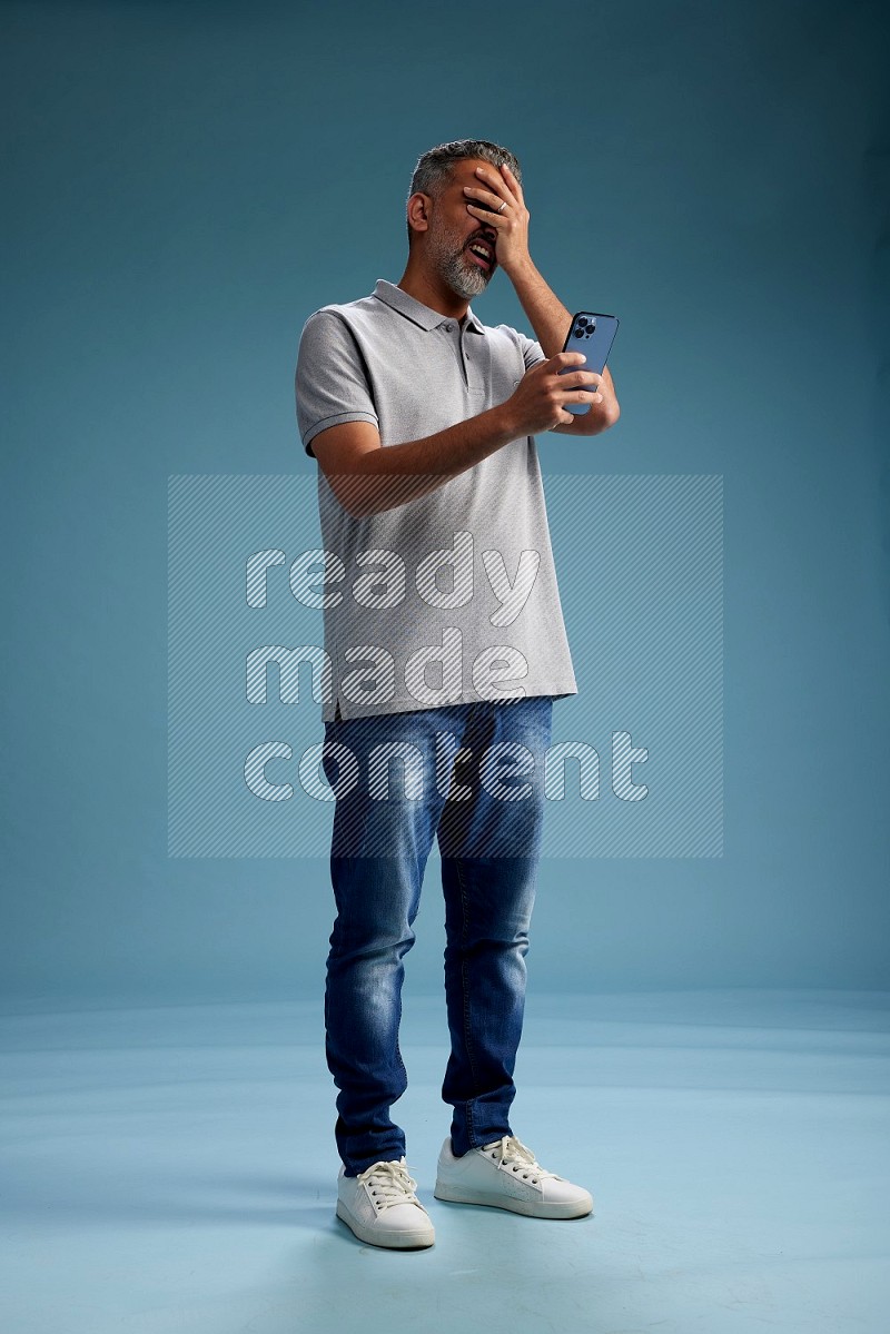 Man Standing texting on phone on blue background