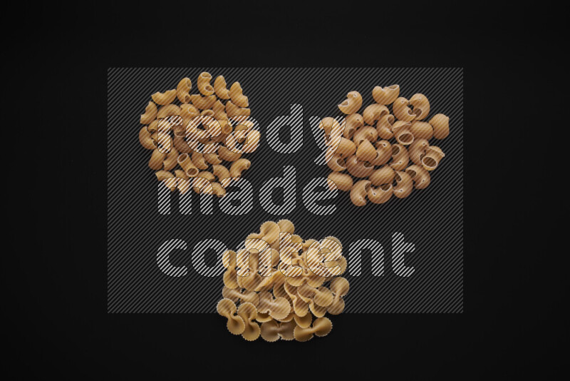 Different pasta types in bunches on black background