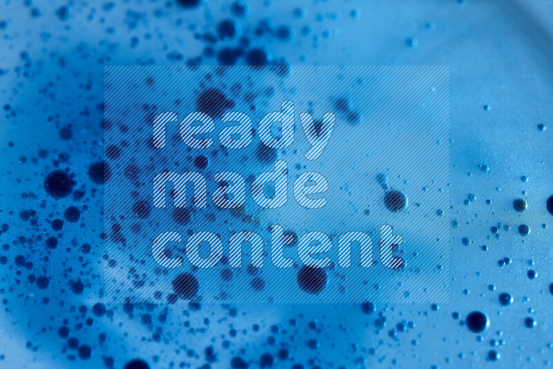 Close-ups of abstract blue watercolor drops on oil Surface on blue background