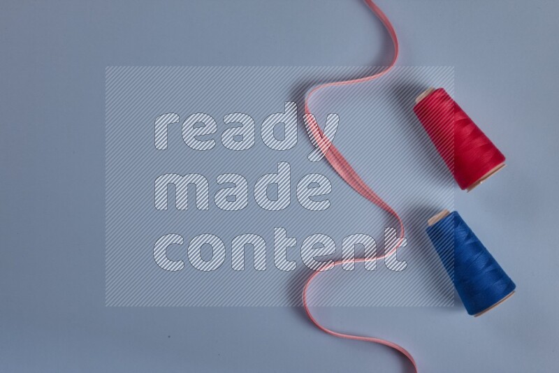 A pink collection of sewing and tailoring tools arranged on a blue background