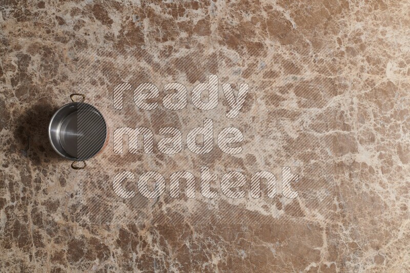 A small copper pot on beige marble background