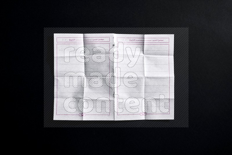 Folded notebook sheet on black background