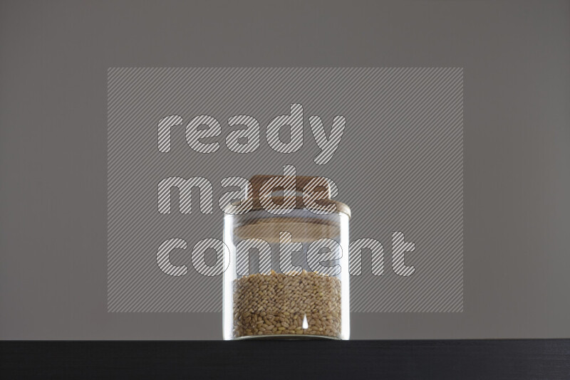 Hulled wheat in a glass jar on black background