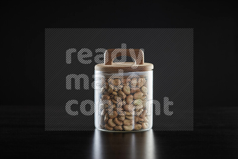 Fava beans in a glass jar on black background