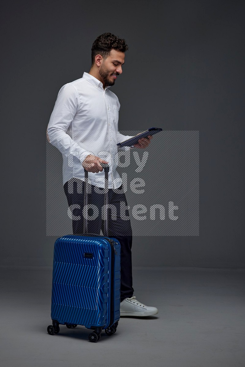 A man wearing smart casual with and pulling a carry-on luggage eye level on a gray background