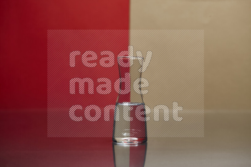 The image features a clear glassware filled with water, set against red and beige background