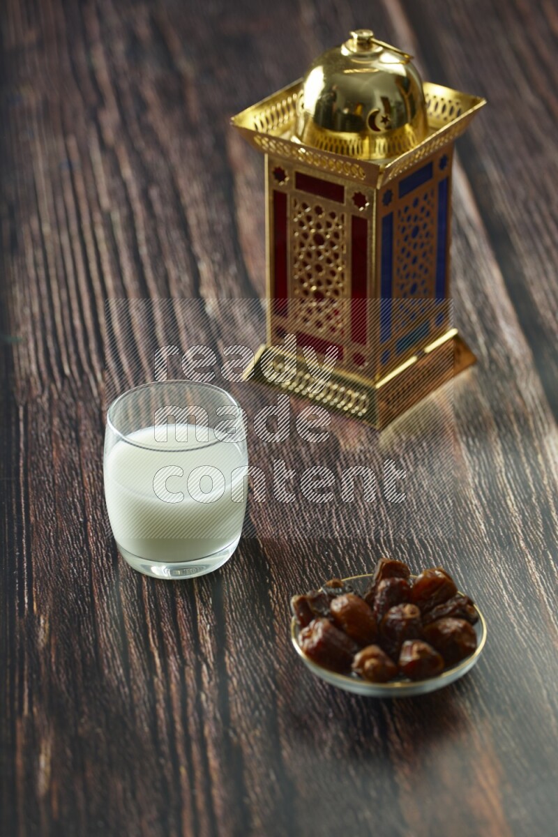 A golden lantern with different drinks, dates, nuts, prayer beads and quran on brown wooden background