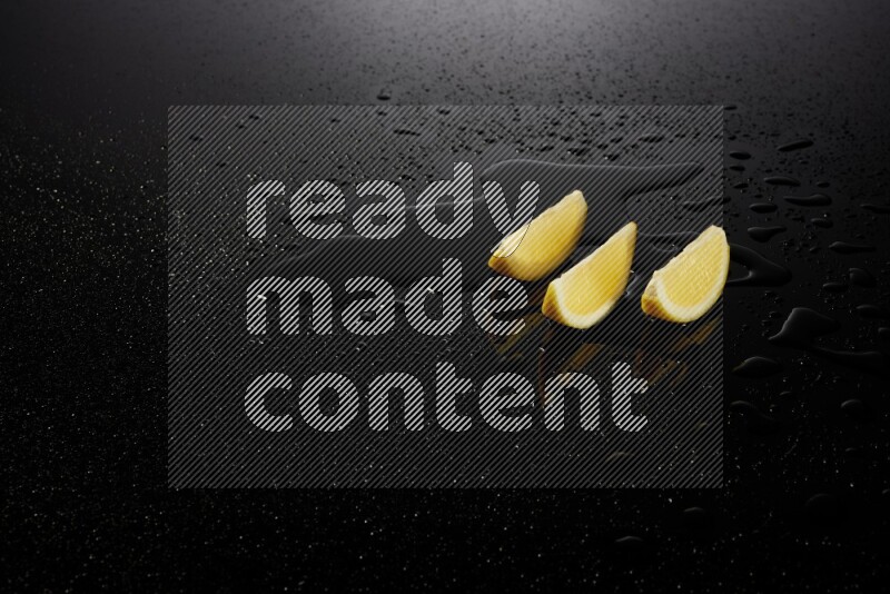 Lemon wedges with water drops, and droplets on black background
