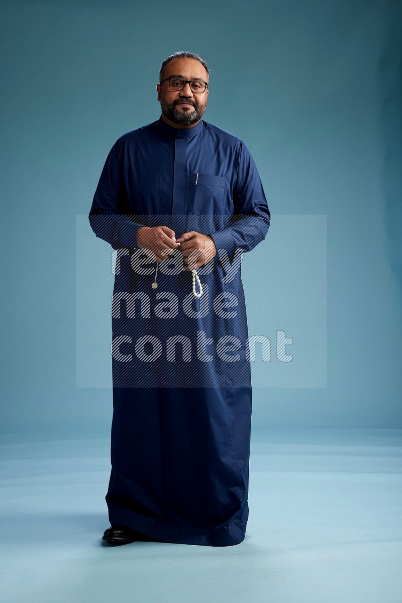 Saudi Man without shimag Standing Interacting with the camera on blue background