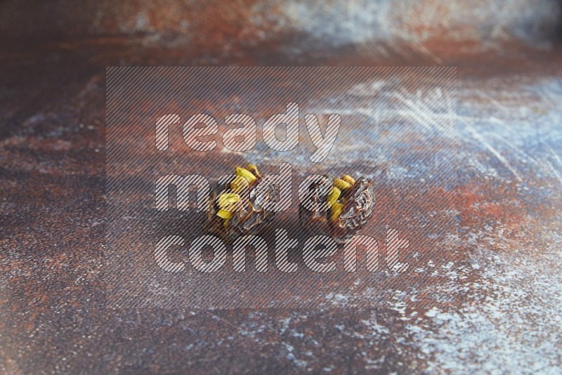 two pistachio stuffed madjoul dates on a rustic reddish background