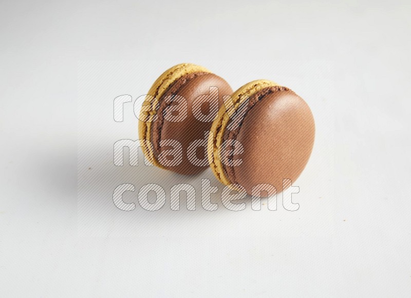 45º Shot of two Yellow and Brown Chai Latte macarons on white background