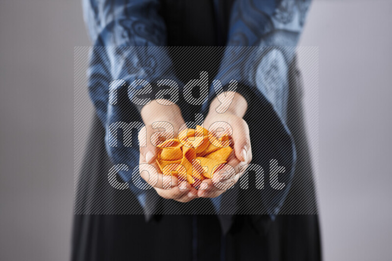 Woman in abaya holding different kinds of snacks in different positions
