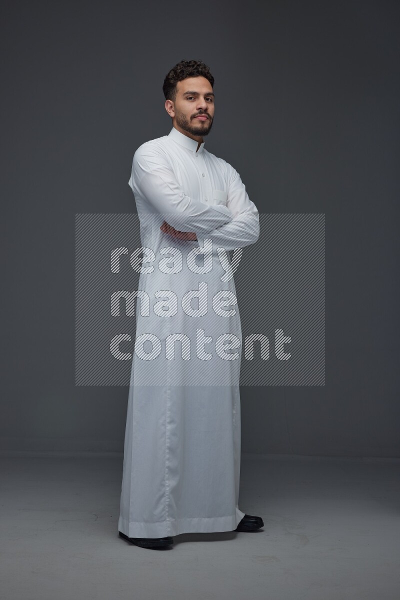 A Saudi man wearing Thobe standing and making different poses eye level on a gray background