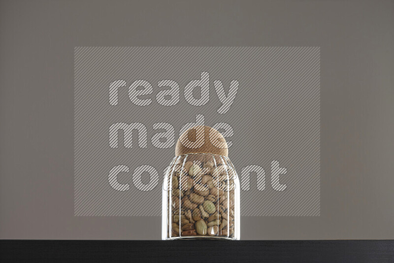 Fava beans in a glass jar on black background