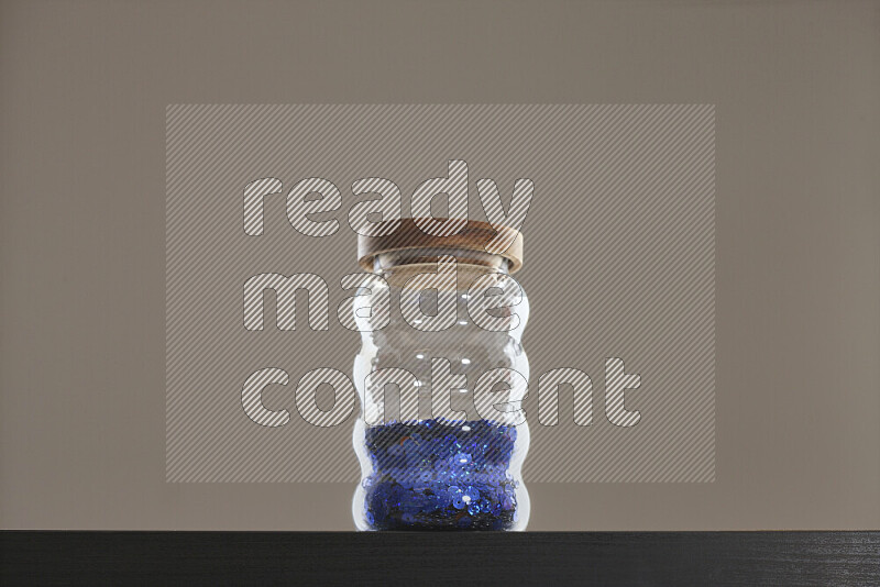 Sequins in a glass jar on black background