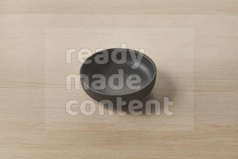 A black pottery bowl on light wooden background