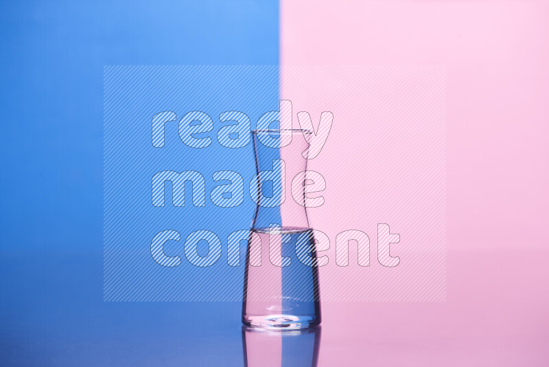 The image features a clear glassware filled with water, set against blue and rose background