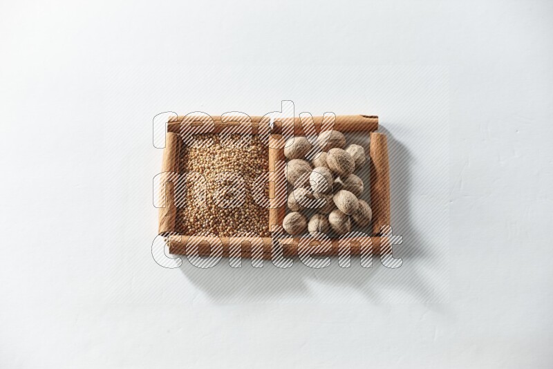 مربعان من أعواد القرفة ممتلئان بحبوب الخردل وجوزة الطيب علي خلفية بيضاء