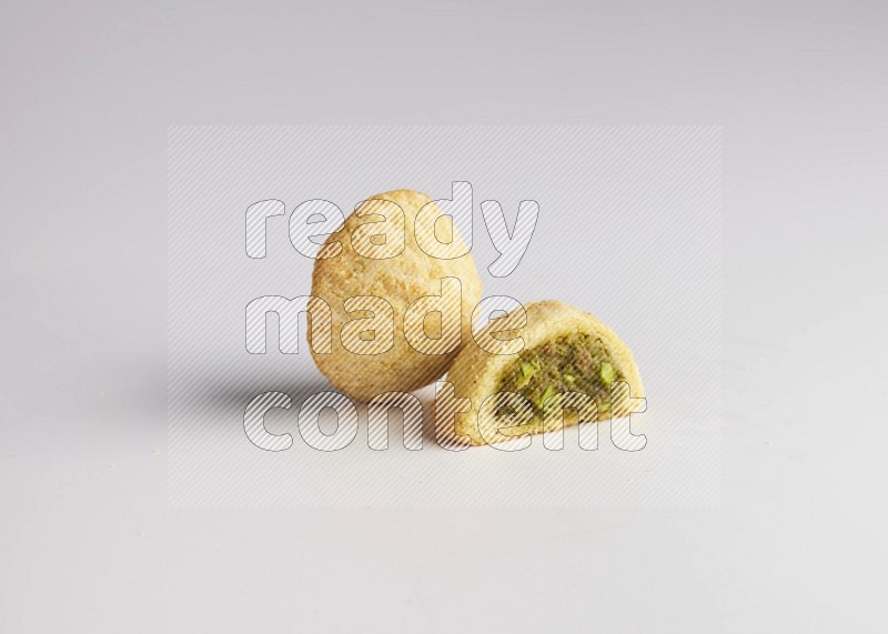 Two Pieces of Maamoul filled with pistachio paste  one of them is cut direct on white background