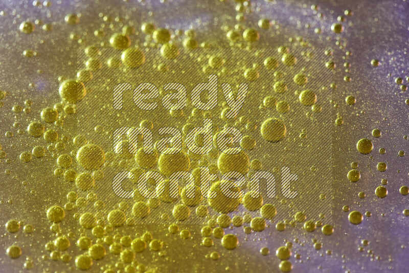 Close-ups of abstract yellow watercolor drops on oil Surface on pink background