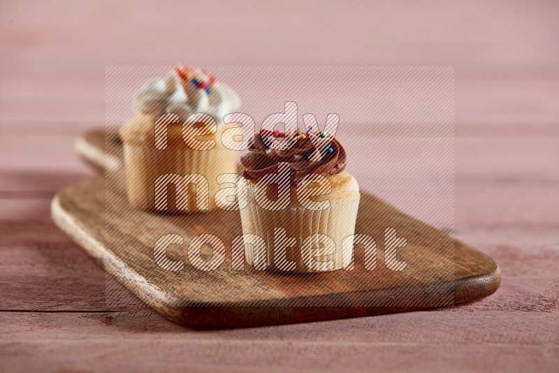 Vanilla mini cupcake topped with chocolate cream on a wooden board