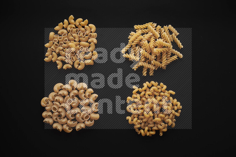 Different pasta types in bunches on black background