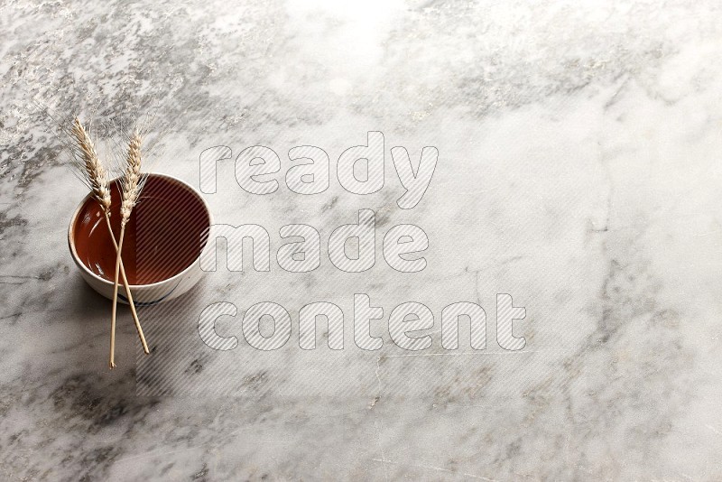 Wheat stalks on Brown Pottery Bowl on grey marble flooring, 45 degree angle