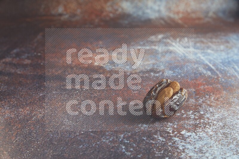one almond stuffed madjoul date on a rustic reddish background