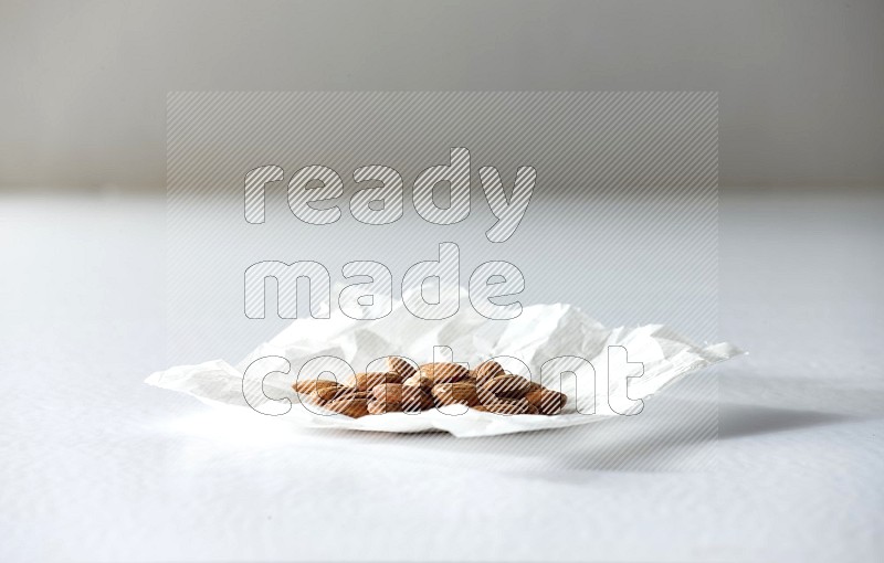 Peeled almonds on a crumpled piece of paper on a white background in different angles