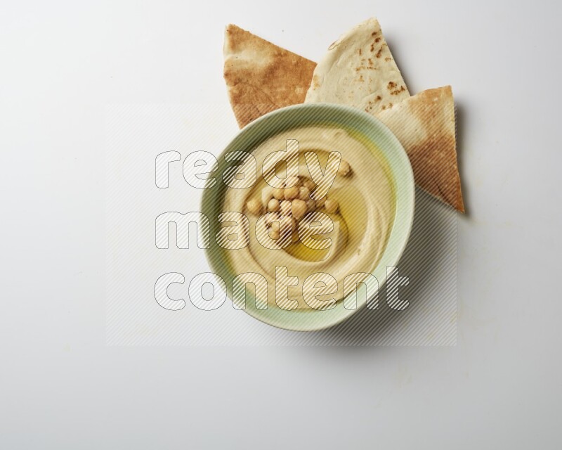 Hummus in a green plate garnished with roasted chickpeas  on a white background