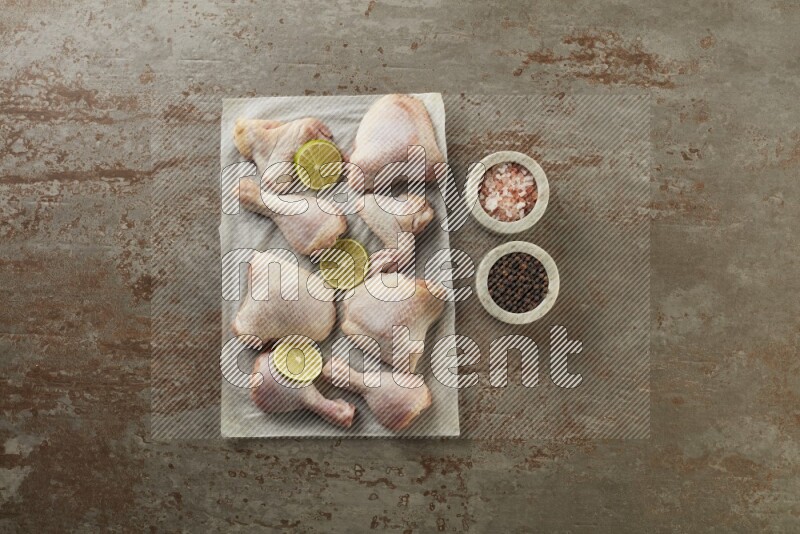Mixed fresh chicken pieces on a parchment paper direct on a textured rustic background