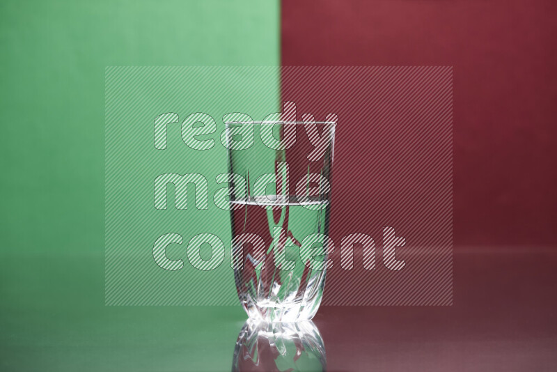 تظهر الصورة أواني زجاجية ممتلئة بالماء موضوعة على خلفية من اللونين الأخضر والأحمر الغامق