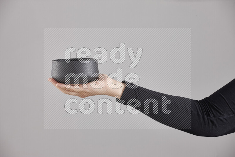 A woman in black abaya holding different pottery essentials in different positions