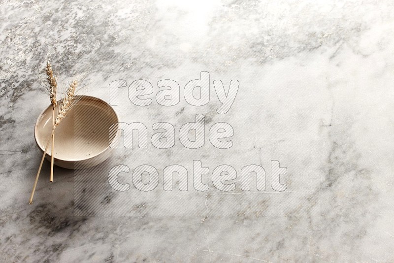 Wheat stalks on Beige Pottery Bowl on grey marble flooring, 45 degree angel
