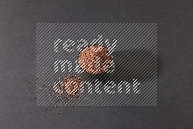 A black pottery bowl full of garden cress seeds on a black flooring