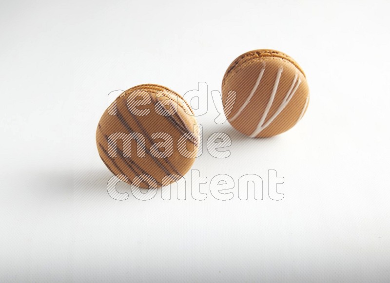 45º Shot of of two assorted Brown Irish Cream, and light brown  Almond Cream macarons on white background