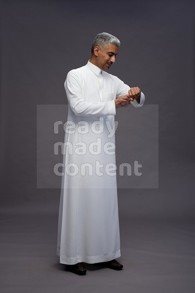 Saudi man wearing thob with neck strap employee badge standing interacting with the camera on gray background