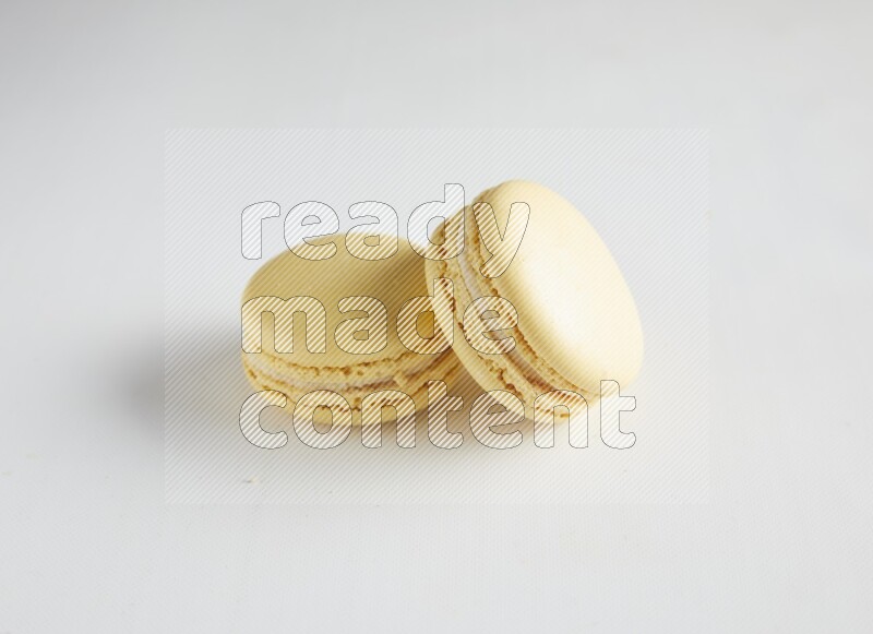 45º Shot of two Yellow Vanilla macarons on white background