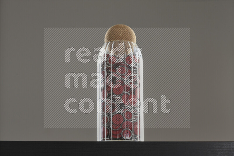 أزرار متنوعة في وعاء زجاجي علي خلفية سوداء